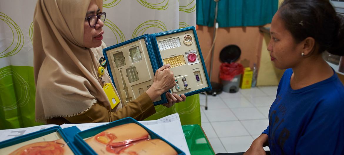 在印度尼西亚南苏拉威西省，一名女顾问在卫生中心向一名妇女介绍节育方法。