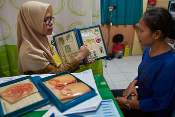 在印度尼西亚南苏拉威西省，一名女顾问在卫生中心向一名妇女介绍节育方法。
