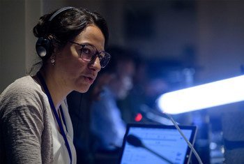 Una intérprete de la ONU , con auriculares y gafas, se encuentra frente a un micrófono en una conferencia.