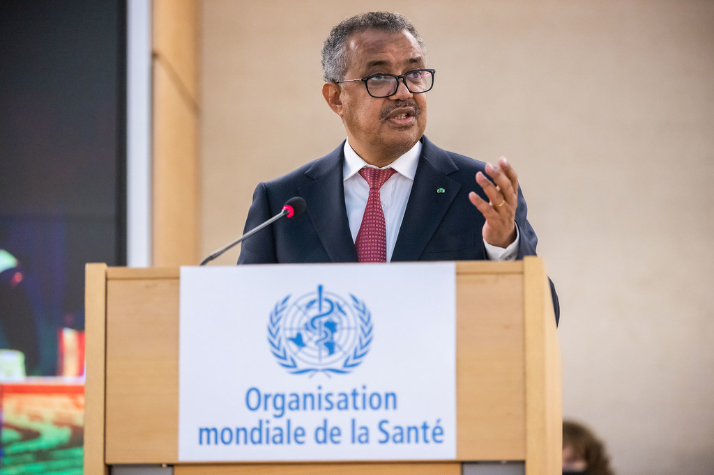 O Dr. Tedros Adhanom Ghebreyesus discursa em um pódio com o logotipo da Organização Mundial da Saúde.