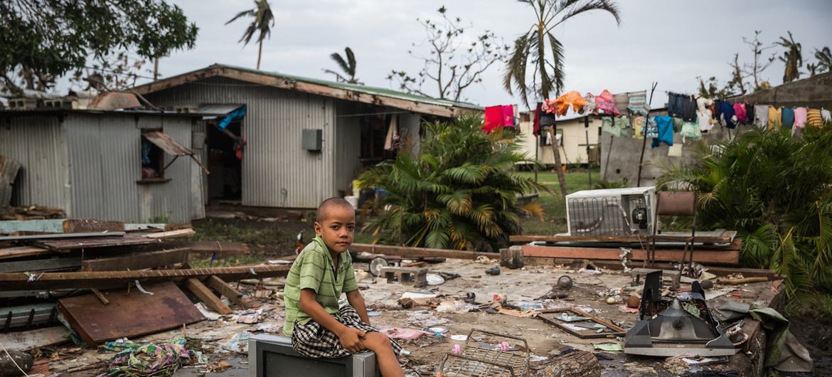 Uraia, de 7 anos, está sentado em um aparelho de TV sobre os restos de sua casa, que foi destruída pelo ciclone Winston em Fiji em 2016.