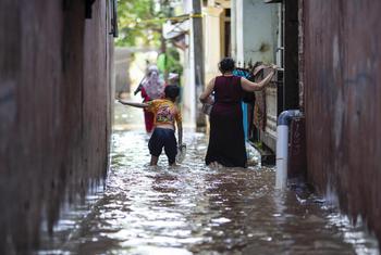 在印度尼西亚首都雅加达的一处受洪水影响的地带，一名男孩和他的母亲在水中行走。