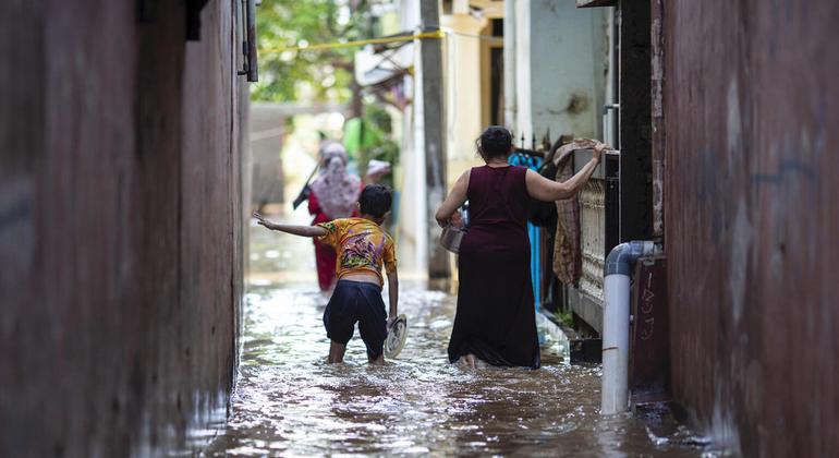 21 फरवरी 2021 को इंडोनेशिया के पूर्वी जकार्ता में, बाढ़ से प्रभावित क्षेत्र में एक लड़का और उसकी माँ, पानी के बीच से जा रहे हैं.
