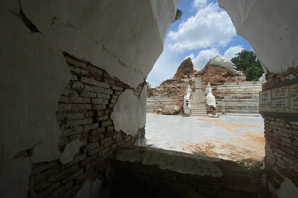 Vue d'une pagode endommagée à Mahaaungmyay, au Myanmar, montrant des briques effondrées et des escaliers en pierre apparents sous un ciel bleu.