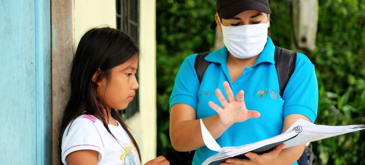 Una niña de 11 años en Ecudor recibe una guía para estudiar durante el cierre de escuelas por la pandemia de COVID-19