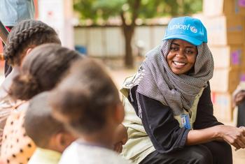 Membro da equipe do Unicef fala com crianças deslocadas em um ponto de encontro em Madani, no centro-leste do Sudão.