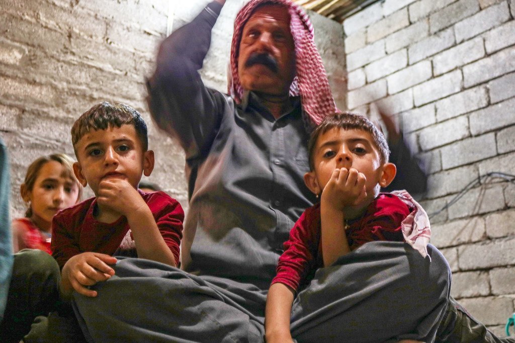 يظهر في الصورة رجل عراقي وأطفاله في مأوى للنازحين في العراق.