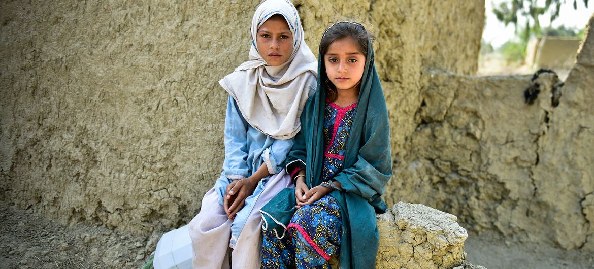 Des jeunes filles sont assises sur le mur endommagé de leur maison en terre cuite, presque détruite lors des inondations de 2022 au Pakistan.