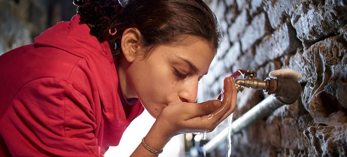 在埃及开罗，一名生活在贫民窟的女孩用家里的水龙头喝水。