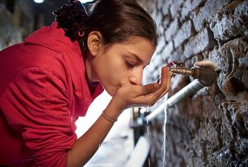 मिस्र की राजधानी काहिरा की एक निर्धन बस्ती में एक लड़की, नल से पानी पीते हुए.