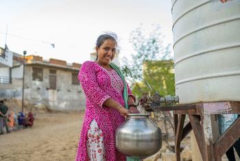 A woman collects drinking water from a common tank installed in a slum in Jaipur, India.