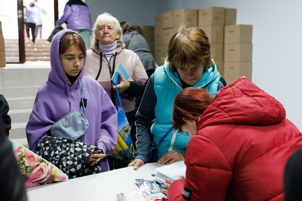 Mujeres y niños reciben kits de ropa de invierno de UNICEF en un centro de distribución en Izium, Ucrania.