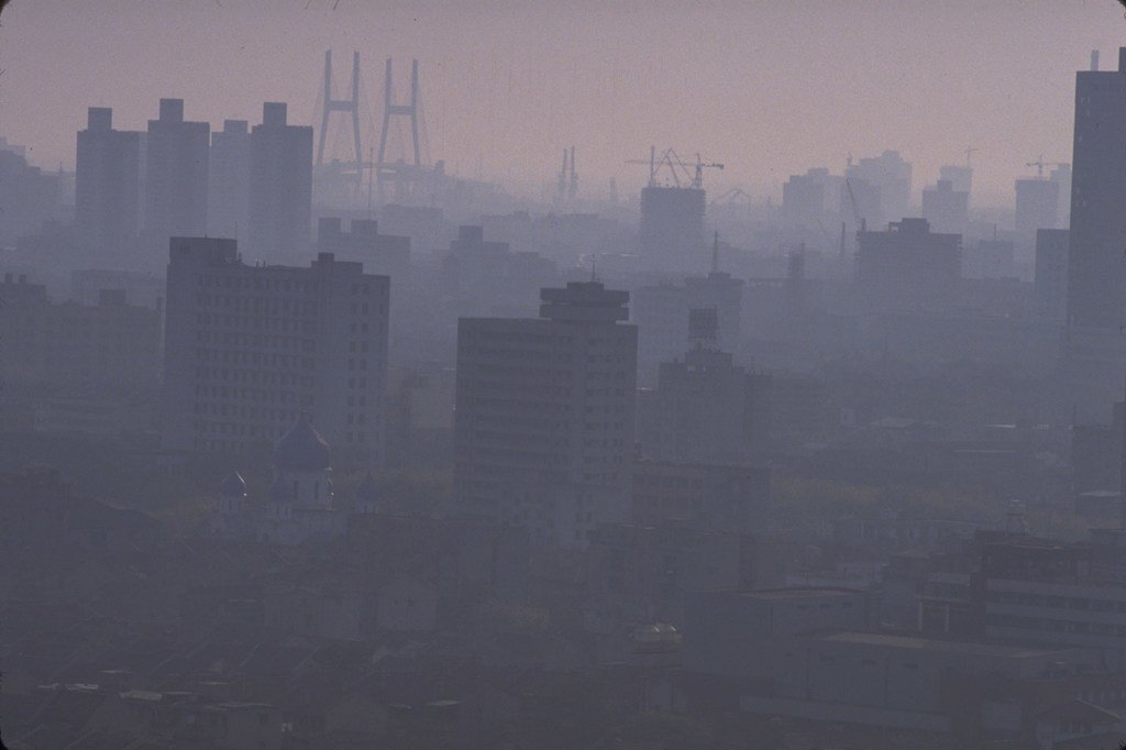 Al anochecer, el cielo de Shanghái se llena de niebla tóxica. A través de la bruma, se pueden distinguir edificios y un puente.