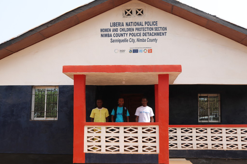 Three men stand on the porch of the newly renovated Women and Children's Protection Centre at Sanniquille Police Station in Liberia.