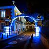 Arco iluminado sobre uma rua em Oeiras, Portugal, à noite, com luzes azuis no edifício e uma ciclovia demarcada.