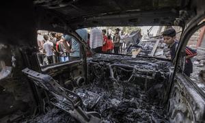 A young boy looks at a burnt vehicle after an Israeli airstrike in the Gaza Strip in 2022.