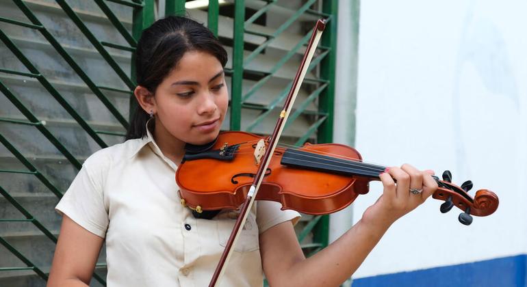 Luisa, víctima del acoso de las bandas en Honduras, toca el violín en su escuela, a través de la lectura, la escritura y la música muestra su lado creativo y su capacidad para encontrar la alegría en diversas formas de expresión personal.
