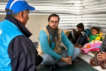 联合国难民署代表让-尼古拉·博兹在约旦阿兹拉克难民营的避难所与叙利亚难民沃达及其五名子女交谈。