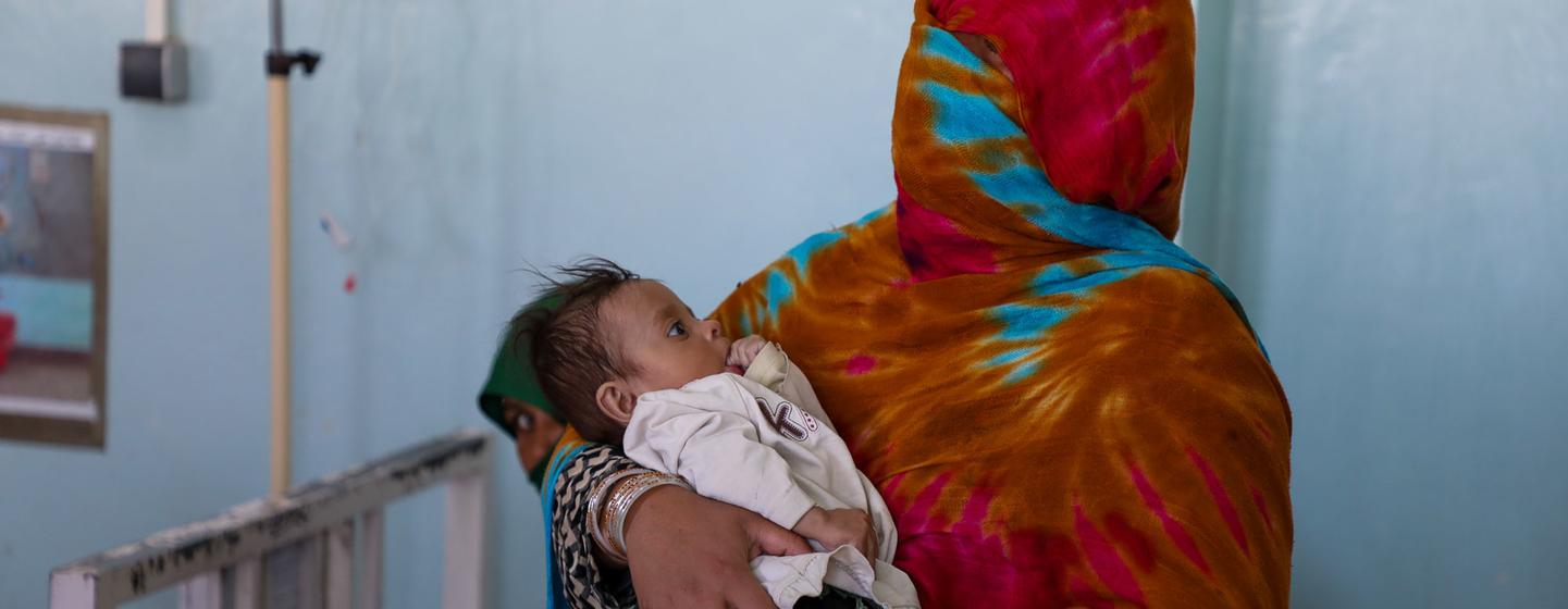 Uma mãe segura seu filho desnutrido no Hospital Regional Mirwais em Kandahar, Afeganistão.