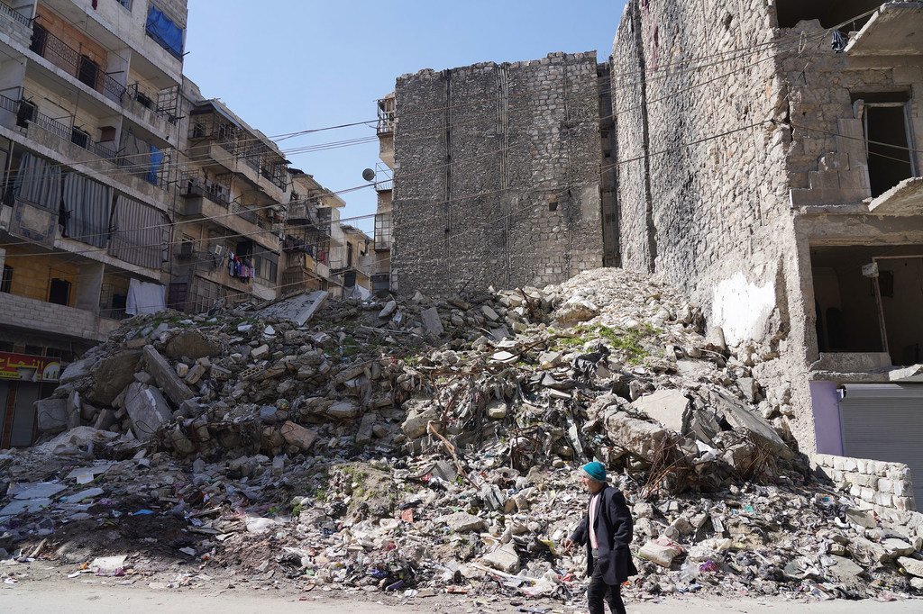 A man walks past a large pile of rubble from destroyed buildings in a street in Aleppo, Syria.