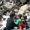 أطفال فلسطينيون في غزة يجلسون بين ركام المنازل المدمرة.