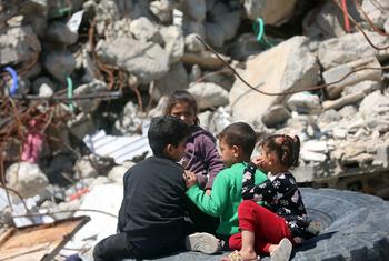 أطفال فلسطينيون في غزة يجلسون بين ركام المنازل المدمرة.