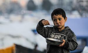 A young boy in Gaza City eats a plate of food.