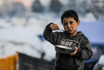 A young boy in Gaza City eats a plate of food.