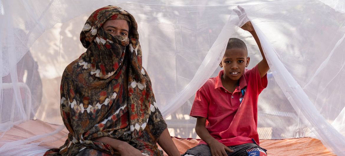 Uma mãe e seu filho sentam-se em uma cama com mosquiteiros tratados com inseticida de longa duração (LLINs) distribuídos pelo Unicef e parceiros no estado de Kassala, Sudão