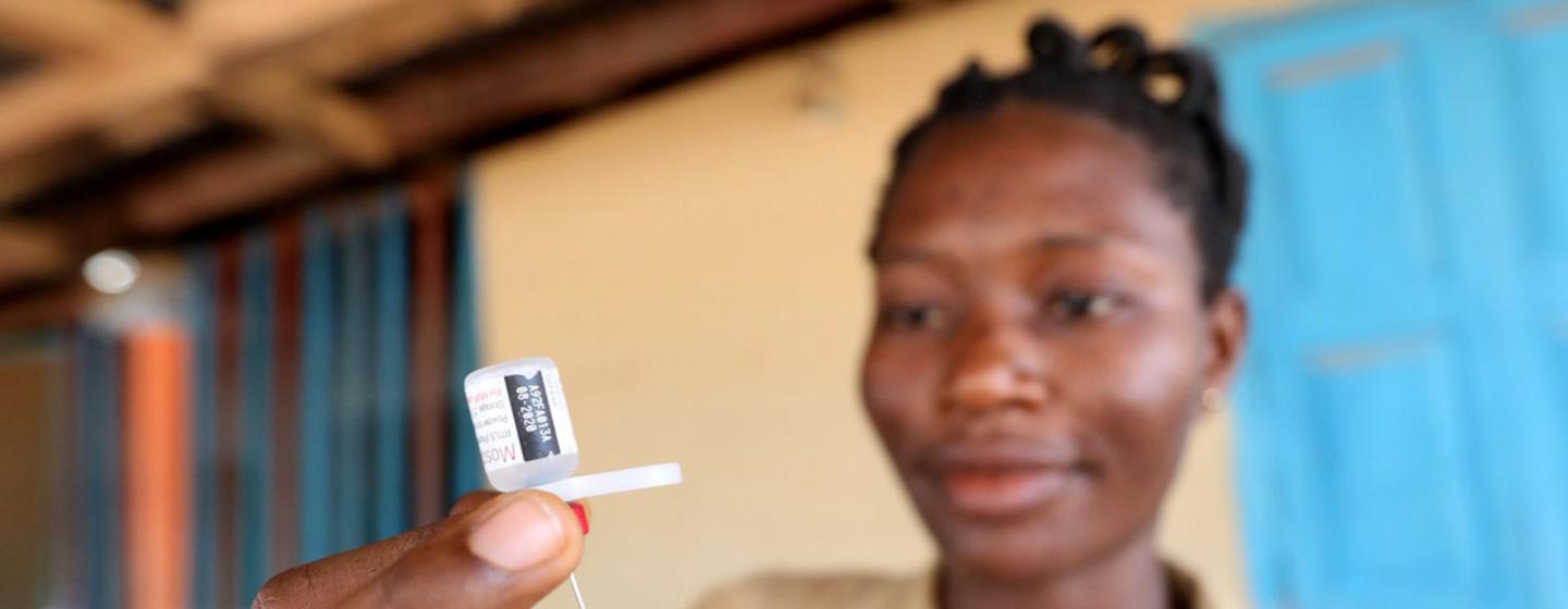 Une infirmière tient une seringue et un flacon de vaccin antipaludique RTS,S.