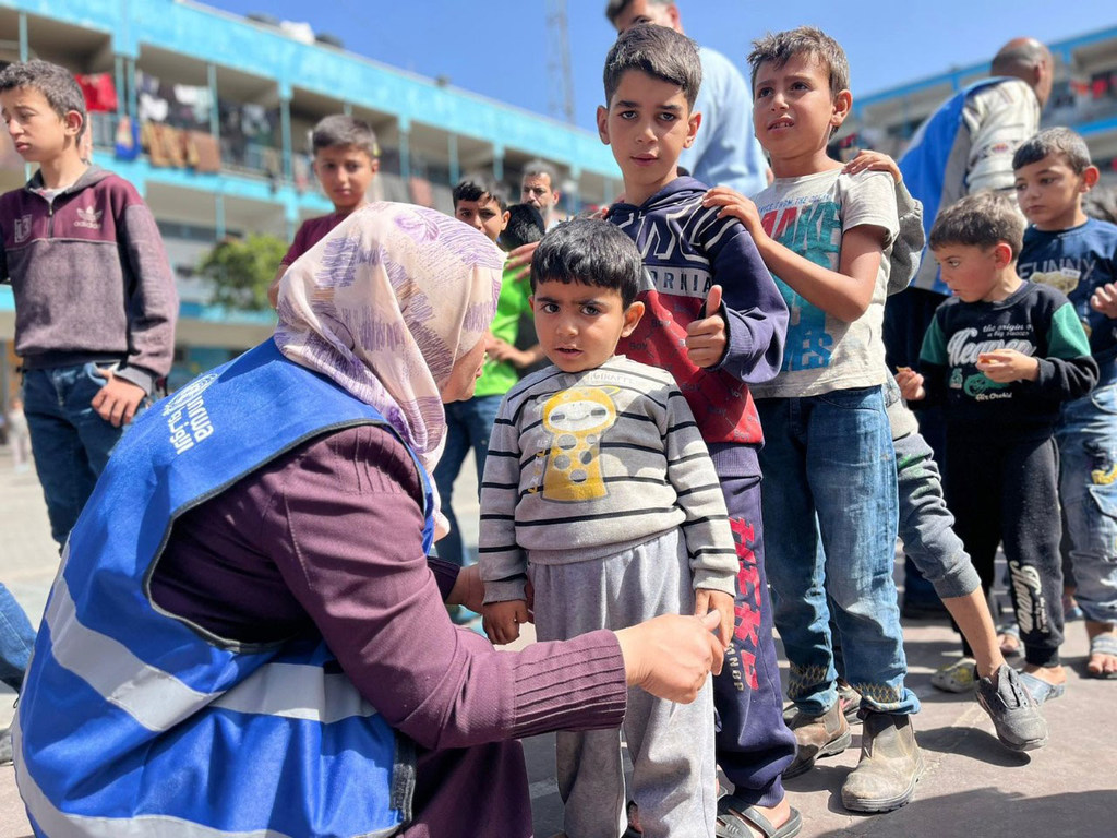 Une employée de l'UNRWA aide des enfants à Gaza.