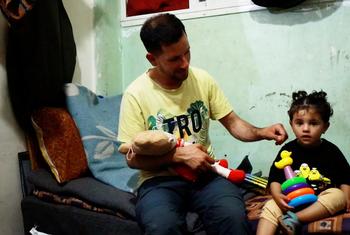 باسم الحبل، صانع محتوى فلسطيني من ذوي الإعاقة يعاني من الصمم نزح من شمال غزة إلى دير البلح، مع طفلته.