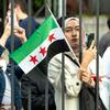 Une femme brandit le nouveau drapeau syrien devant le siège de l'ONU, à New York.
