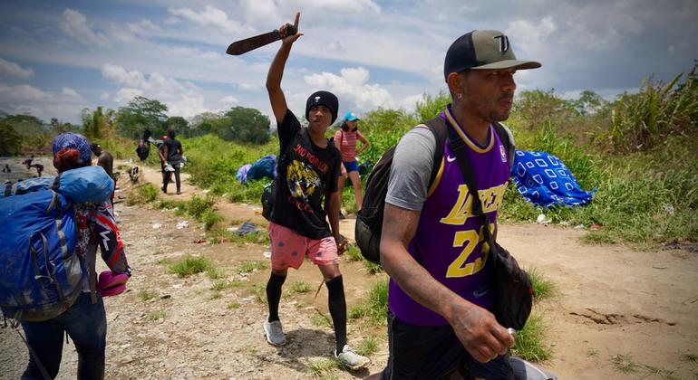 Migrantes exhaustos dan los últimos pasos para salir del Darien Gap y entrar en una comunidad.