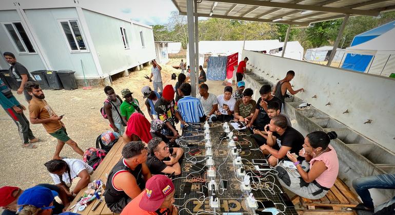 Migrantes y refugiados cargando sus teléfonos en un enchufe de la Estación de Acogida de Migrantes tras cruzar la selva del Darién.