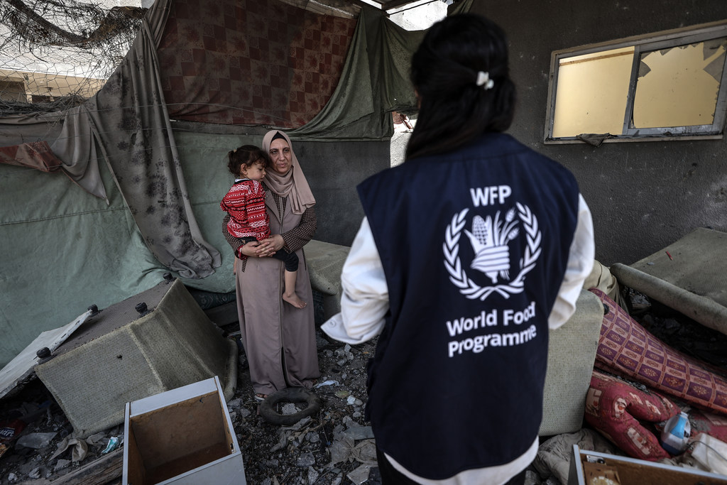 Un voluntario del Programa Mundial de Alimentos visita a una familia desplazada entre los escombros de su casa en Gaza.