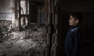 A young boy stands amid the ruins of a classroom in Douma destroyed during the Syrian civil war.