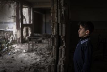 A young boy stands amid the ruins of a classroom in Douma destroyed during the Syrian civil war.