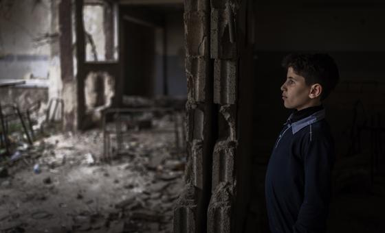 A young boy stands amid the ruins of a classroom in Douma destroyed during the Syrian civil war.
