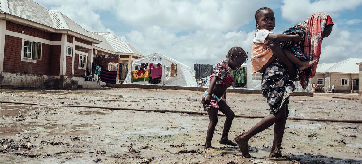 Des enfants marchent dans la boue dans un camp de personnes déplacées à Maiduguri dans le nord-est du Nigéria.