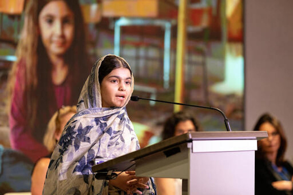ایک نوجوان خاتون وکیل پاکستان میں UNICEF ایک پروگرام کے دوران ایک پوڈیم پر خطاب کر رہی ہے، جو موسمیاتی کارروائی کے بارے میں سامعین سے خطاب کر رہی ہے۔