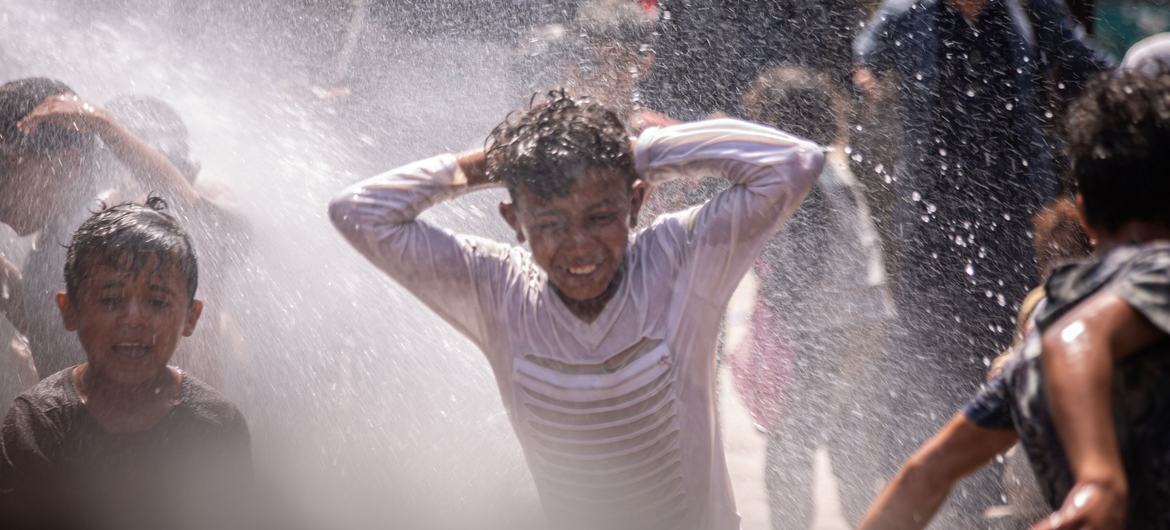 Des enfants jouent avec le jet d'une pompe à eau réhabilitée dans un camp de personnes déplacées à Ibb, au Yémen.