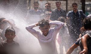 Children play with the spray from a rehabilitated water pump in a displaced camp in Ibb, Yemen.