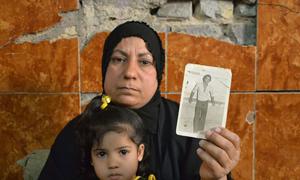 A woman in Iraq displays a photograph of her husband who disappeared more than 30 years ago.