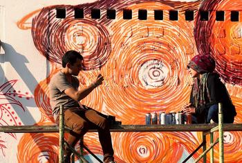 一群女性涂鸦艺术家在危地马拉城绘制橙色壁画，以支持联合国妇女署和16日运动。