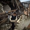 En Ukraine, un garçon de neuf ans aide sa mère à nettoyer les décombres de leur maison fortement endommagée, en vue de couvrir les zones ouvertes avec du plastique à l'approche de l'hiver.