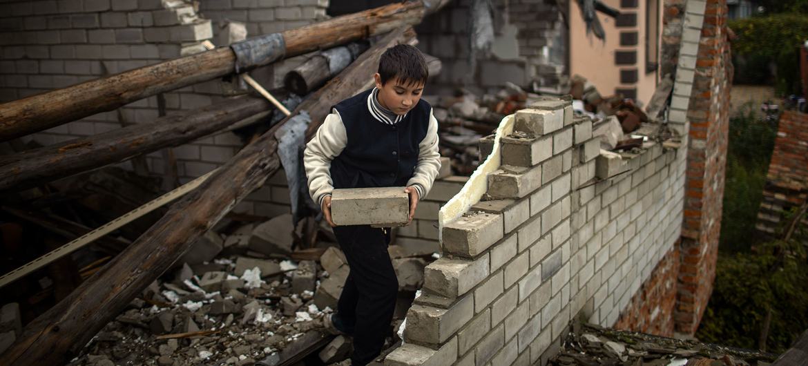 Девятилетний мальчик помогает своей матери убирать завалы из их сильно поврежденного дома 