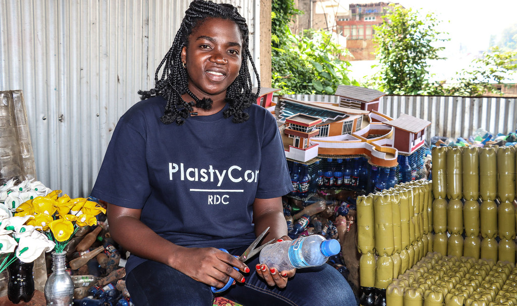 Nicole Menemene, entrepreneuse de Plastycor, est assise, tenant une bouteille en plastique et des ciseaux, dans son centre de recyclage à Bukavu, Sud-Kivu, RDC.