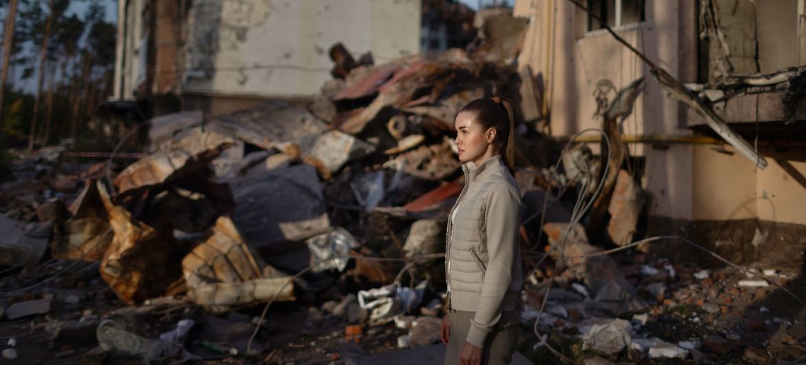 A young Ukrainian woman walks amidst the ruins of her grandparents’ home in Irpin.