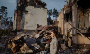 A young Ukrainian woman walks amidst the ruins of her grandparents’ home in Irpin.